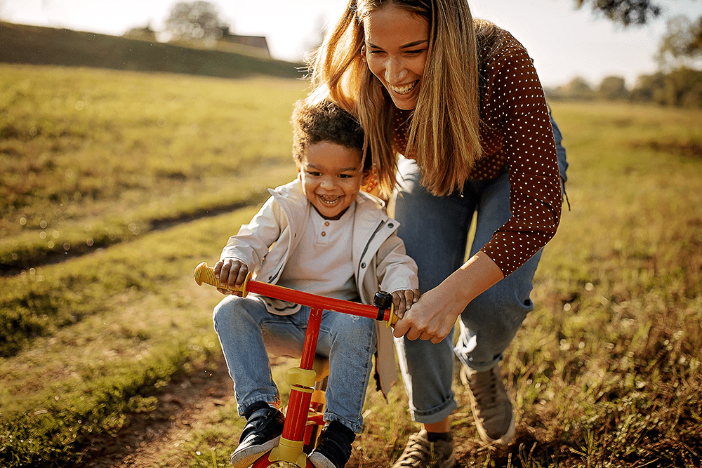 Mom helping her son learn to ride a bike