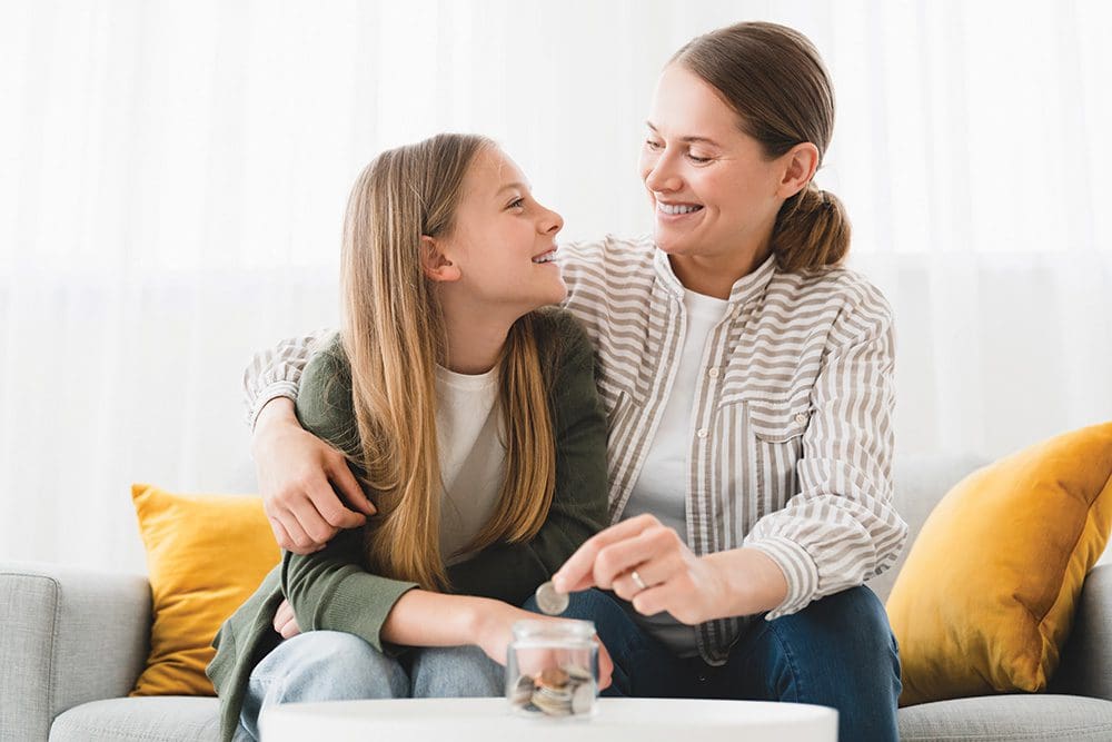Mother and daughter saving money in a coin bank