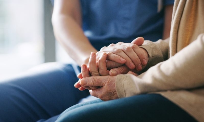 Cropped shot of a senior woman holding hands with a nurse.