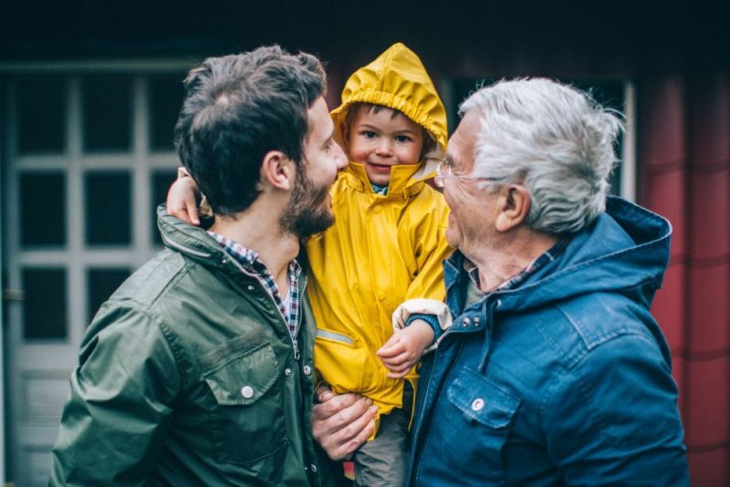 A grandfather, father, and son smiling.