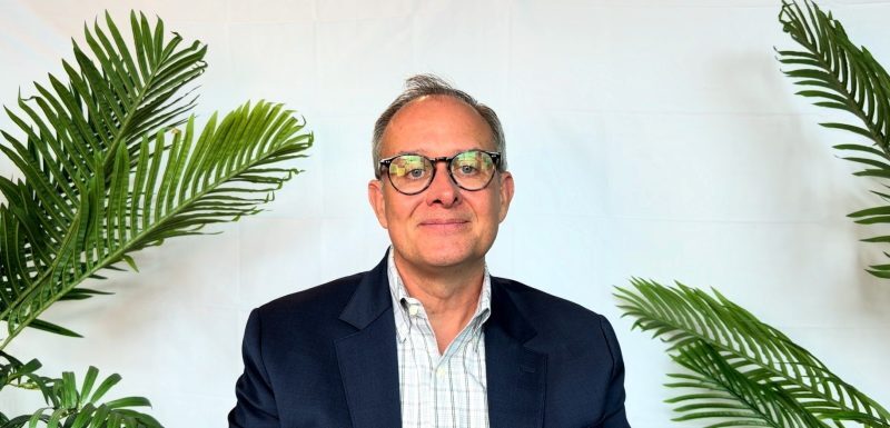 Chris Campbell in front of a background smiling at the camera.